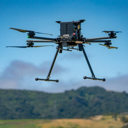 Inspired Flight IF1200A with Blue Herelink Ground Control Station, heavy-lift drone in flight against a cloudy sky
